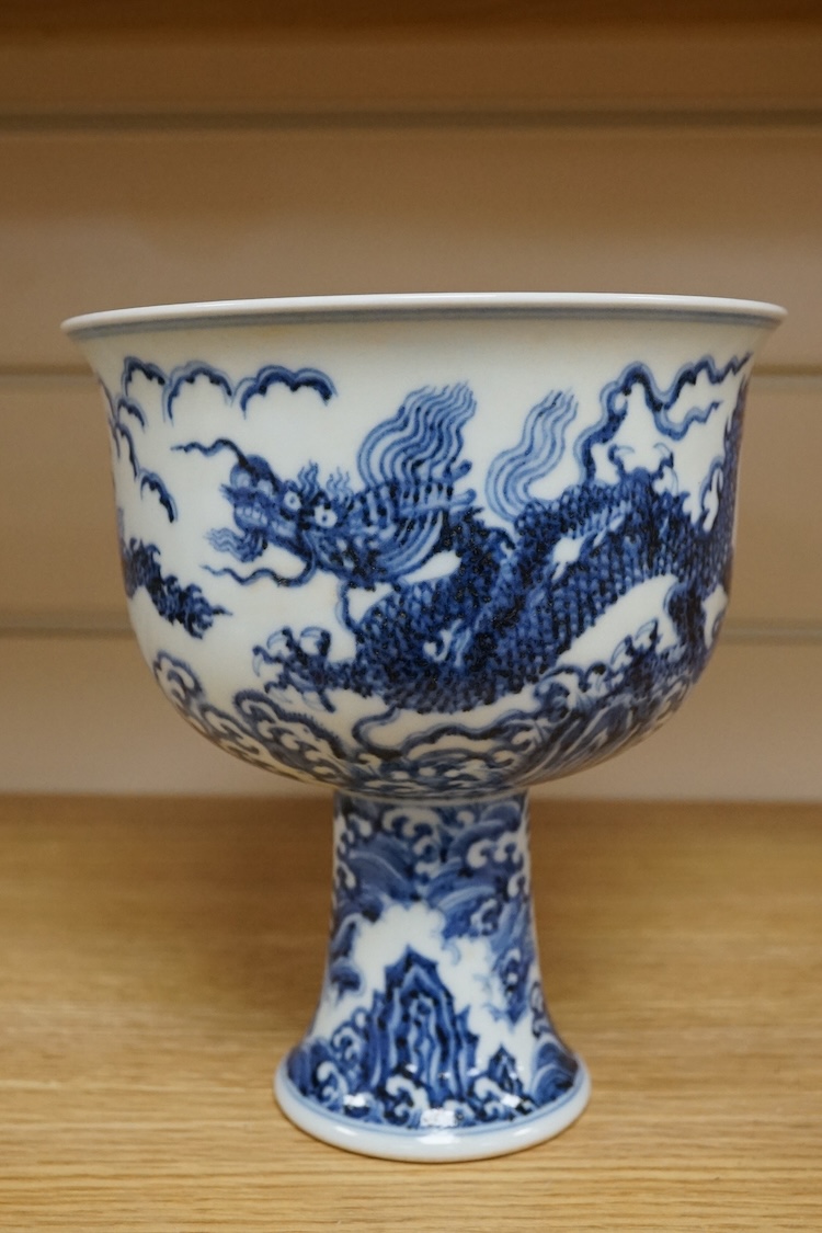 A Chinese blue and white stem bowl, painted with dragons in underglaze blue, 18cm high